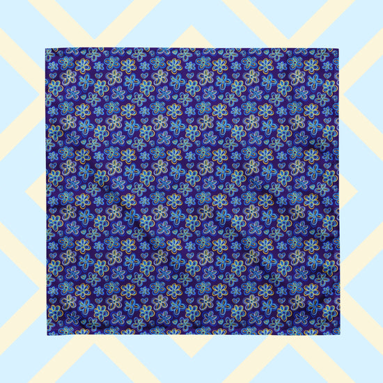 The Bloomscape Bandana by My Favourite Colour is Rainbow features a design of large flowers and small hearts in shades of blue and yellow on a royal blue background.