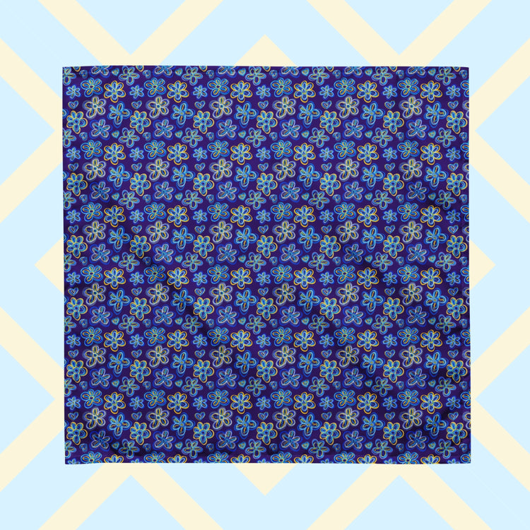The Bloomscape Bandana by My Favourite Colour is Rainbow features a design of large flowers and small hearts in shades of blue and yellow on a royal blue background.