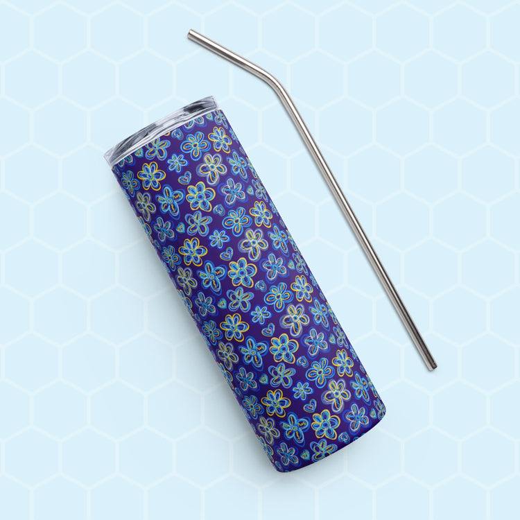 A Bloomscape Stainless Steel Tumbler by My Favourite Colour is Rainbow, featuring a design of large flowers and small hearts in shades of blue and yellow on a royal blue background shown on its side with a matching metal straw.