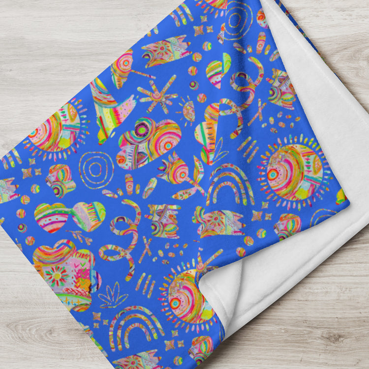 The Blue Summer Sorbet Throw Blanket by My Favourite Colour is Rainbow features vibrant blue fabric with a white underside and cosy, multicolored abstract patterns like swirls, sun shapes, crescents, and circles for a playful look.