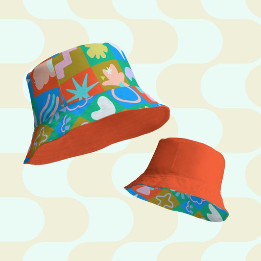 Two views of the Colour Block Reversible Bucket Hat by My Favourite Colour is Rainbow, with one side featuring a vibrant checkerboard of abstract shapes and florals in a retro colour palette.  The reverse side is a matching solid orange colour.
