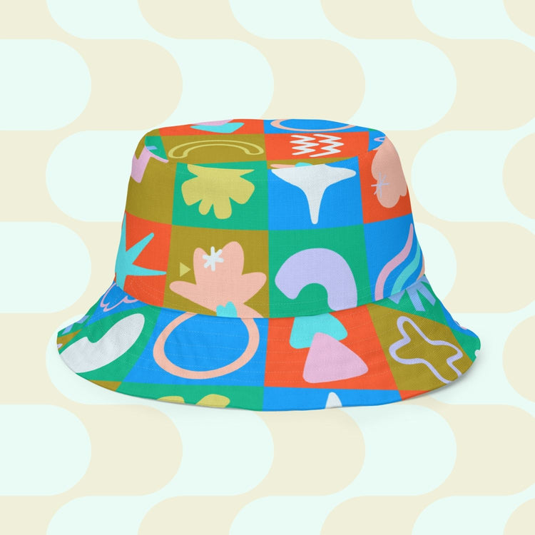 The Colour Block Reversible Bucket Hat by My Favourite Colour is Rainbow features a vibrant checkerboard pattern with abstract shapes in green, orange, blue, and more.