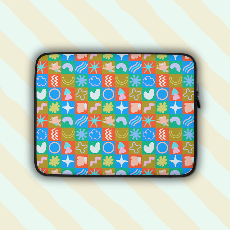 The Colour Block Laptop Sleeve by My Favourite Colour is Rainbow features vibrant abstract shapes like circles, stars, waves, and flowers in colours with a vintage vibe.  It is set against a pastel background.  The print is on only one side of the laptop sleeve, the other side is black.