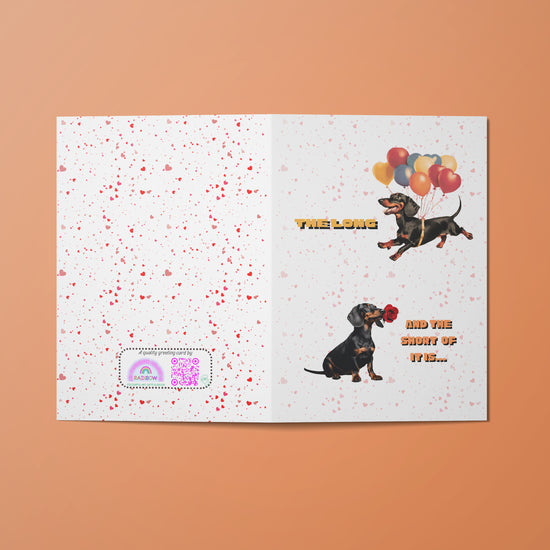 The Perfect Match Dachshund Valentines Card by My Store features a speckled white cover with two sausage dogs: one flying with balloons, the other with a red clown nose. It reads The Long and the Short of it and includes a rainbow QR code in the lower left corner.