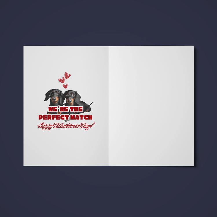 The Perfect Match Dachshund Valentines card from My Store showcases two cute sausage dogs cuddled amidst red hearts, with We’re the perfect match. Happy Valentines Day! on a crisp white background, beautifully capturing loves essence.