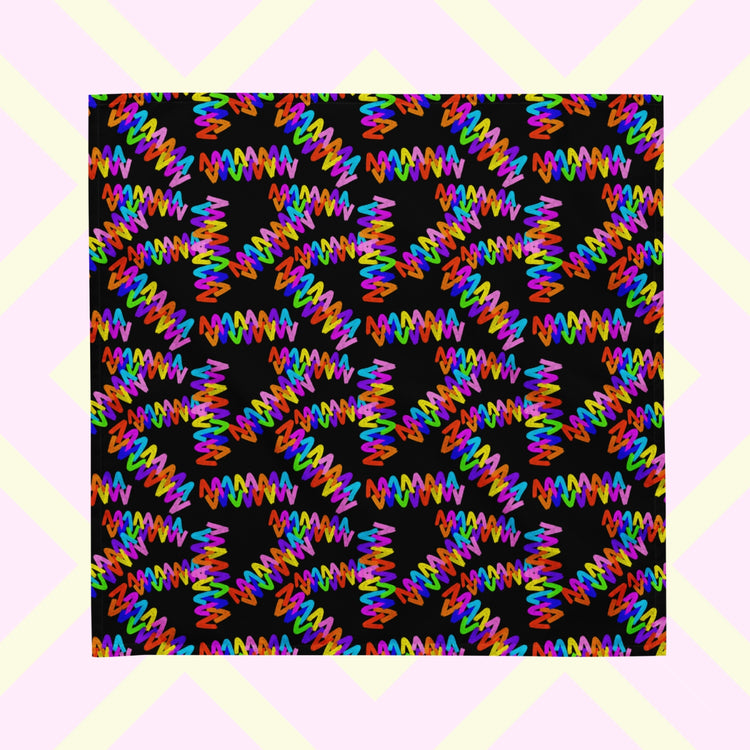 The Electric Zigzag Bandana by My Favourite Colour is Rainbow displays a striking abstract pattern of colourful zigzag lines in red, blue, purple, and green on a black square background.