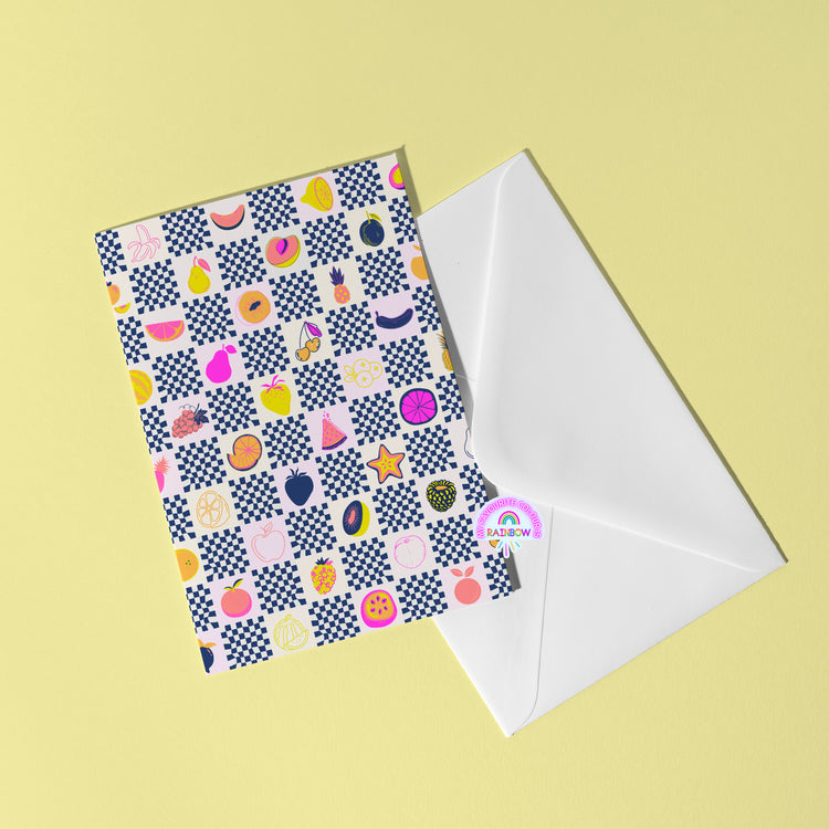 The Fruit Salad Greeting Card by My Store showcases colorful fruit and geometric patterns. Apples, pears, and papayas appear among stars and circles on a yellow backdrop, partially emerging from a white envelope with a small rainbow logo visible.