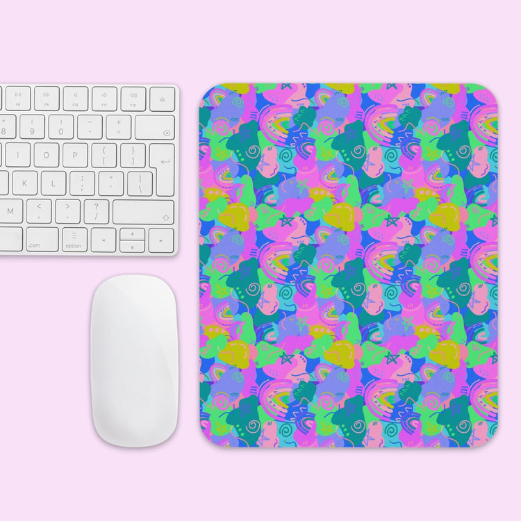 The Funfetti Mouse Pad by My Favourite Colour is Rainbow features a vibrant abstract pattern in blue, green, pink, and yellow tones. Its shown on a light pink surface with a white computer keyboard and mouse.
