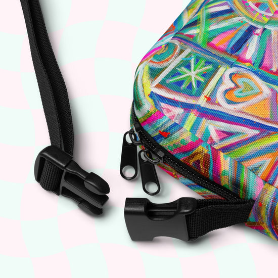 The My Favourite Colour is Rainbow Geometric Rainbow Mini Crossbody Bag features a vibrant geometric heart and triangle print, adjustable straps with plastic buckles, zippers, all on a light pink and mint green checkered background.
