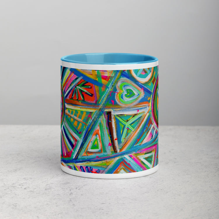 The My Favourite Colour is Rainbows Geometric Rainbow Mug features a vibrant abstract design with triangles, circles, and hearts in bright blue, green, red, and orange hues. This ceramic mug has a light blue interior and rests elegantly on a light surface.