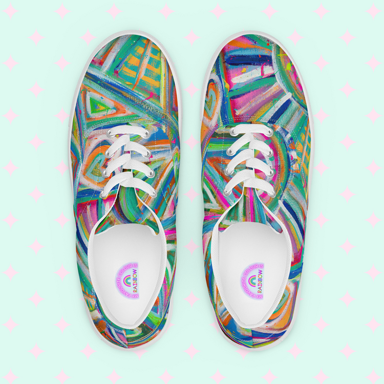 Top view of My Favourite Colour is Rainbows Geometric Rainbow Canvas Sneakers showcasing vibrant abstract patterns in green, orange, purple, and blue hues. The shoes sit on a light mint background with pink star patterns.