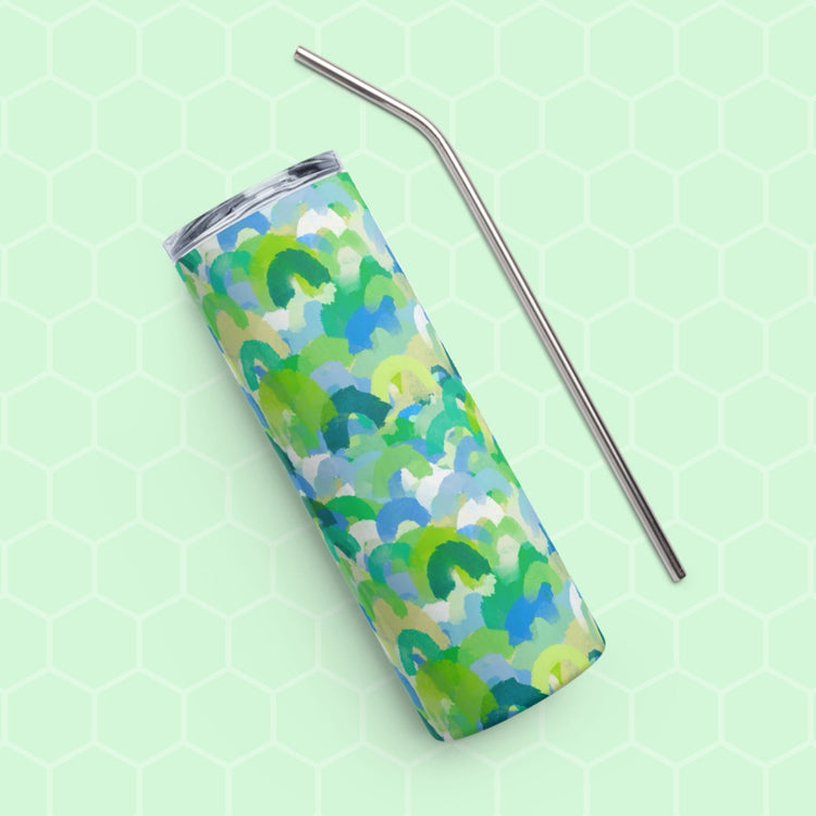 The Green Rainbow Stainless Steel Tumbler by My Favourite Colour is Rainbow, featuring a vibrant green, blue, and light blue abstract pattern with a metal straw, sits on a light green hexagon-patterned background.