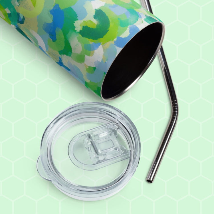 The Green Rainbow Stainless Steel Tumbler by My Favourite Colour is Rainbow features a blue and green abstract pattern, transparent lid, and metal straw. It lies on its side against a pastel green honeycomb-patterned background, ideal for eco-friendly hydration.