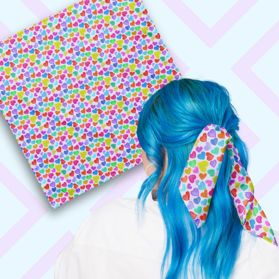 Two views of the 'Heart Attack' Bandana by My Favourite Colour is Rainbow.  At top left, a flat lay of the bandana.  At bottom right, a person with vibrant blue hair is seen from behind, wearing the bandana in her hair.  The bandana features a vibrant, cheerful pattern of densely packed, colourful hearts in pink, blue, purple, green, and orange on a light background.