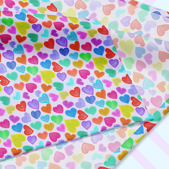 A closeup of the 'Heart Attack' Bandana by My Favourite Colour is Rainbow featuring a vibrant, cheerful pattern of densely packed, colourful hearts in pink, blue, purple, green, and orange on a light background. The design is printed on only one side of the bandana.