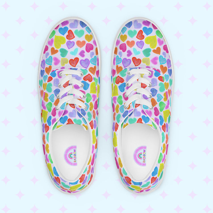 Introducing the My Favourite Colour is Rainbow's Heart Attack Canvas Sneakers, adorned with vibrant multicoloured hearts in red, blue, purple, and green. These sneakers feature white laces and soles.  The inside of the shoe is white with My Favourite Colour is Rainbow branding on the footbed.