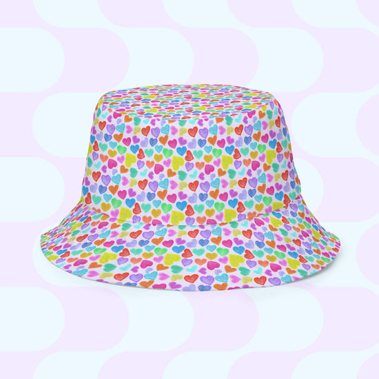 The Heart Attack/Watercolour Rainbow Reversible Bucket Hat by My Favourite Colour is Rainbow features small multicolored hearts and a pale blue and white circular design. Available in various sizes, its the perfect stylish addition to any fashion-forward wardrobe.