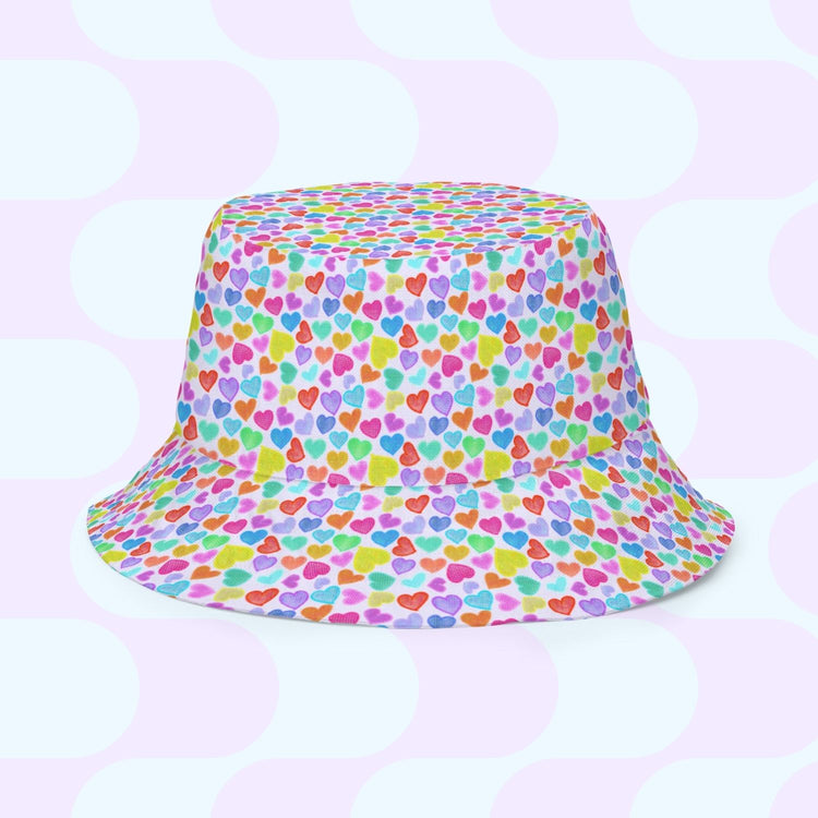 The Heart Attack/Watercolour Rainbow Reversible Bucket Hat by My Favourite Colour is Rainbow features small multicolored hearts and a pale blue and white circular design. Available in various sizes, its the perfect stylish addition to any fashion-forward wardrobe.