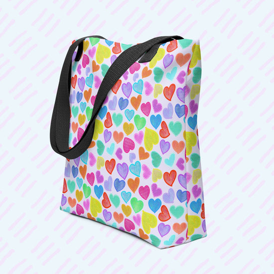 My Favourite Colour is Rainbows Heart Attack Tote Bag features a vibrant pattern of pink, orange, yellow, blue, and purple hearts on a light background.  This version has a black strap.