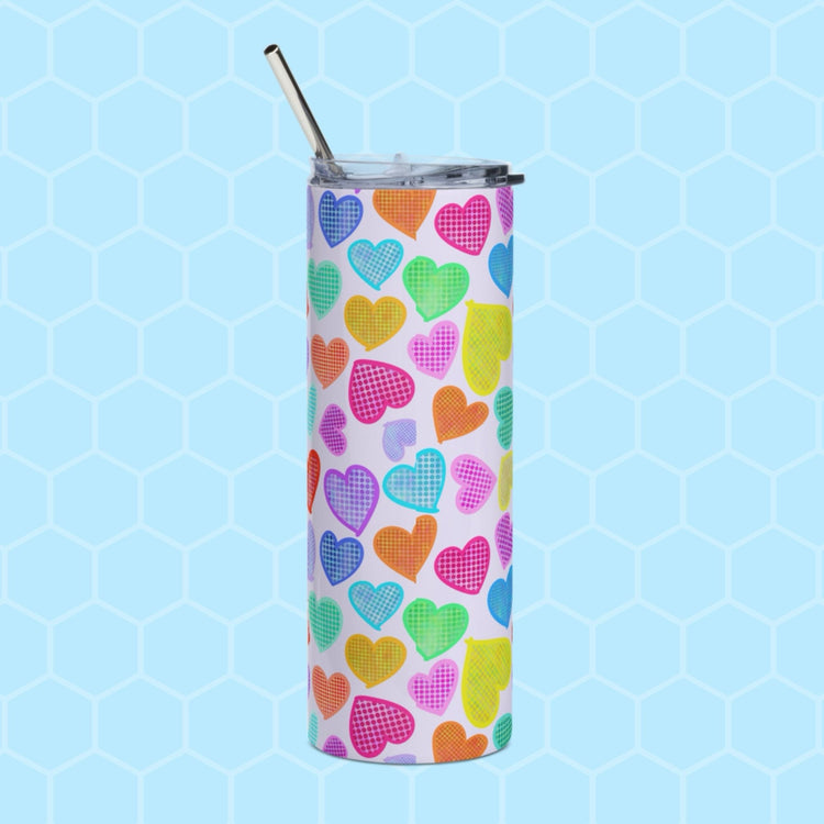 The Heart Attack Stainless Steel Tumbler by My Favourite Colour is Rainbow, featuring a colorful heart pattern and sleek metal straw, stands against a light blue honeycomb background.