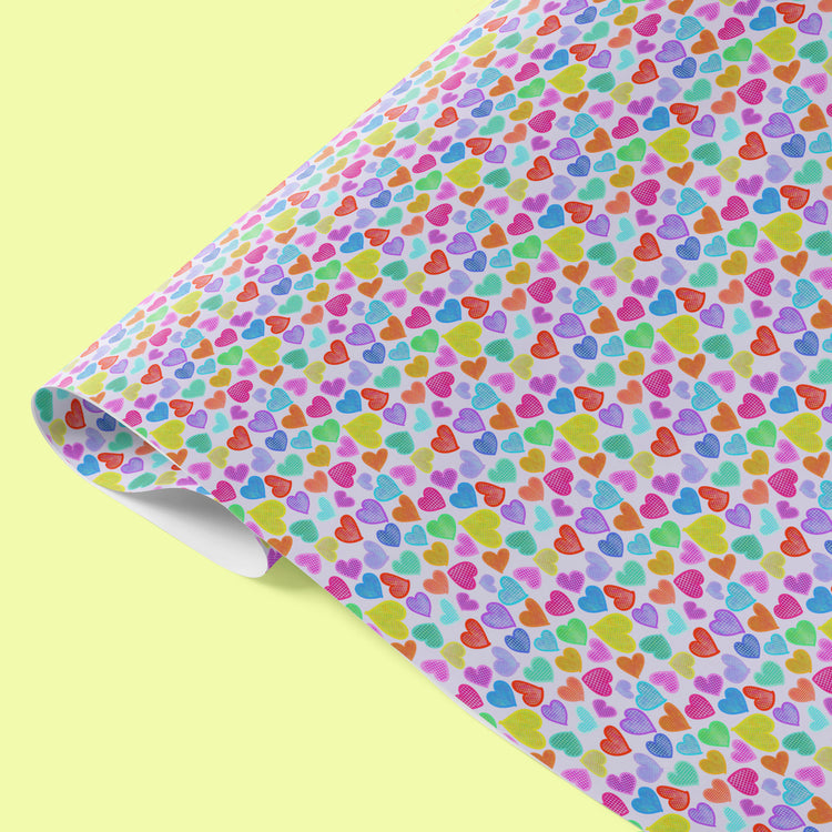 Heart Attack Wrapping Paper Sheets by My Favourite Colour is Rainbow feature vibrant hearts in pink, green, blue, orange, and purple on a light yellow background, creating a cheerful and eye-catching eco-friendly gift wrap.