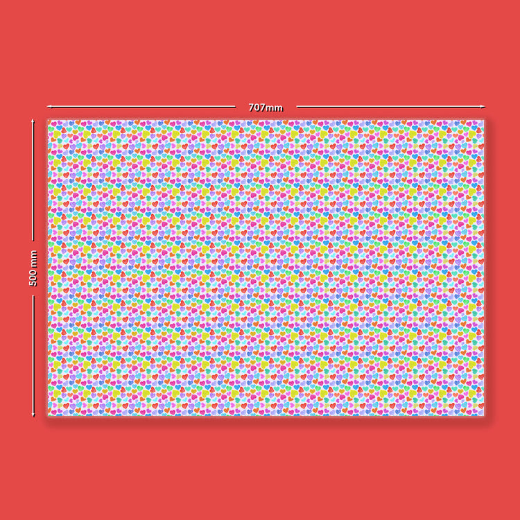 The Heart Attack Wrapping Paper Sheets by My Favourite Colour is Rainbow showcase a white rectangular sheet with vibrant red, blue, green, yellow, and pink polka dots on a bold red background. Measuring 707mm wide by 500mm tall, theyre perfect for eco-friendly gifting.