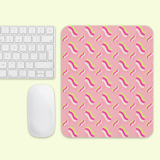 A white keyboard and mouse sit beside the Iced Vovo Mouse Pad by My Favourite Colour is Rainbow, featuring diagonal wavy lines in yellow, white, and pink on a light yellow background.
