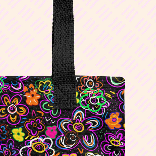 A close-up of the In the Midnight Garden Tote Bag by My Favourite Colour is Rainbow showing the sturdy black handle  a the vibrant abstract floral pattern in neon pink, orange, green, and blue on black.