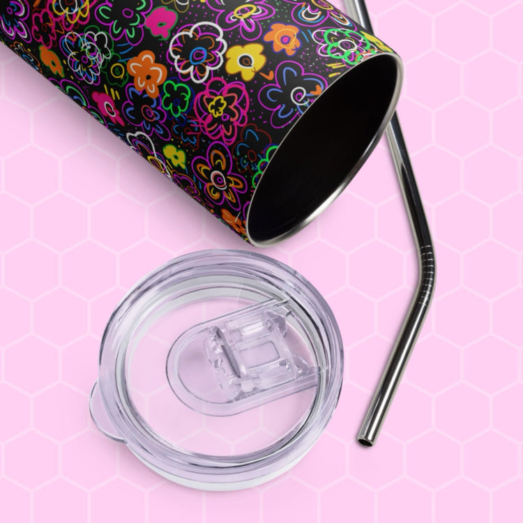 The In the Midnight Garden Stainless Steel Tumbler by My Favourite Colour is Rainbow sits on a pink hexagonal-patterned background, accompanied by a clear plastic lid and sleek metal straw, adding an eco-friendly touch to your drinkware collection with its colorful floral design.