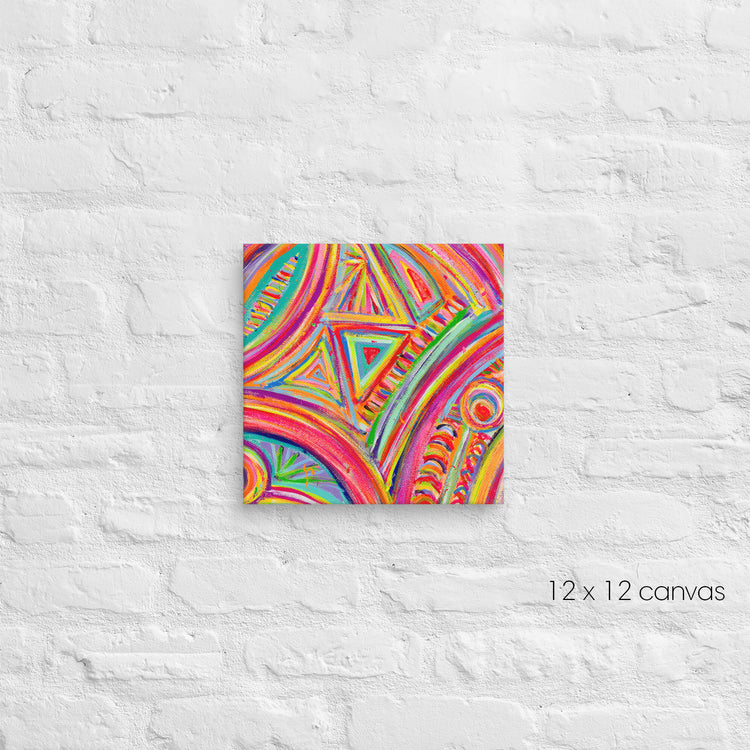 A vibrant 12x12 square canvas from My Favourite Colour is Rainbow named Karma Kaleidoscope showcases abstract patterns with swirling lines and geometric shapes in orange, blue, yellow, and green, mounted on a textured white brick wall.
