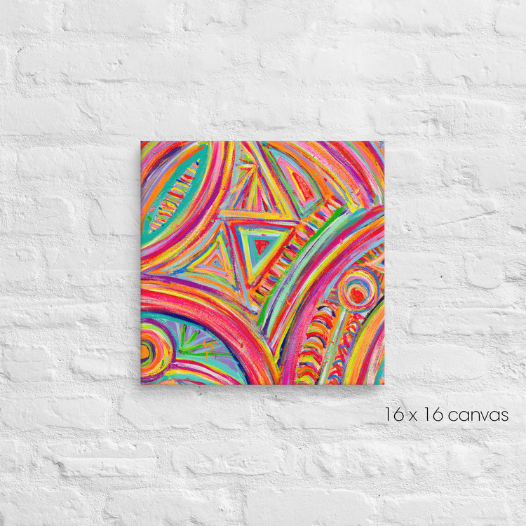 The Karma Kaleidoscope Canvas Artwork by My Favourite Colour is Rainbow showcases abstract circular and triangular patterns in vibrant blue, pink, green, yellow, and orange on a 16x16 canvas against a white brick wall.
