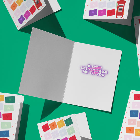 The Love Letter Valentines Card by My Store is open on a green background surrounded by similar cards. Inside, the text reads A love letter from me to you in pink. Each card features colorful envelope designs that bring rainbow joy to their covers.