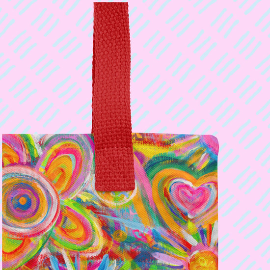 A close-up of the Love in Neon Tote Bag by My Favourite Colour is Rainbow showing the sturdy read handle and part of the design featuring my Love in Neon painting, with vibrant hearts and abstract flowers in pinks, greens, yellows, and blues.