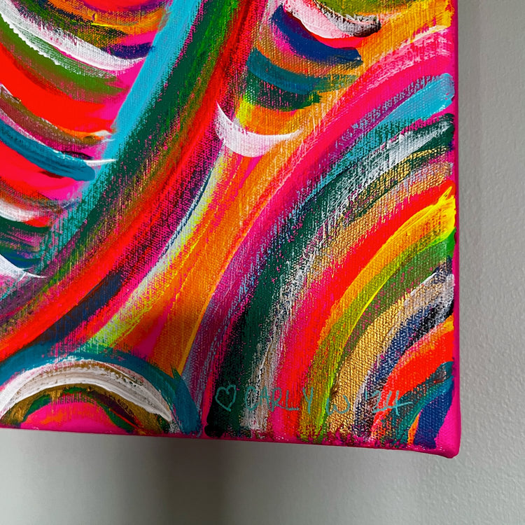 Close-up of the Neon Candy Floss Original Painting by My Store: vibrant acrylic on canvas with swirling neon pink, orange, green, and blue hues. A small outlined heart and signature adorn the bottom right corner. This dynamic rainbow artwork pops against a plain wall backdrop.