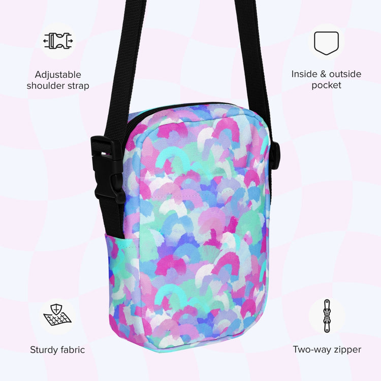An infographic highlighting features of the Pastel Rainbow Mini Crossbody Bag by My Favourite Colour is Rainbow: adjustable shoulder strap, inside and outside pocket, sturdy canvas fabric and a two-way zipper.