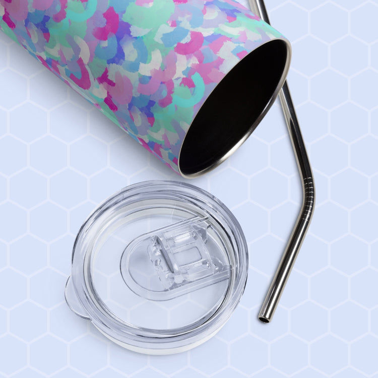 The Pastel Rainbow Stainless Steel Tumbler by My Favourite Colour is Rainbow lies on its side with a clear plastic lid and metal straw beside it. The light blue background with a subtle hexagonal pattern enhances its colorful abstract design.