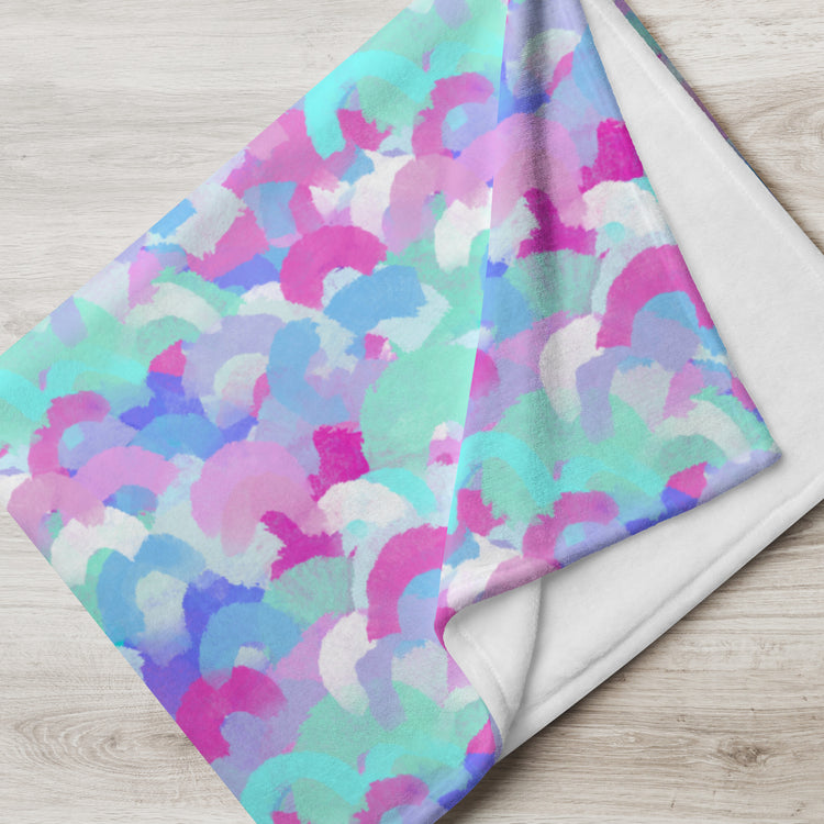 My Favourite Colour is Rainbows Pastel Rainbow Throw Blanket, featuring vivid abstract brushstrokes in soft pink, blue, purple, and mint green hues, lies unfolded on a light wooden surface.