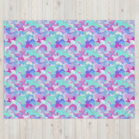 A cozy space is adorned with a vibrant design of overlapping pastel semicircles in pink, blue, purple, and green, reminiscent of the Pastel Rainbow Throw Blanket by My Favourite Colour is Rainbow against a light wooden backdrop.