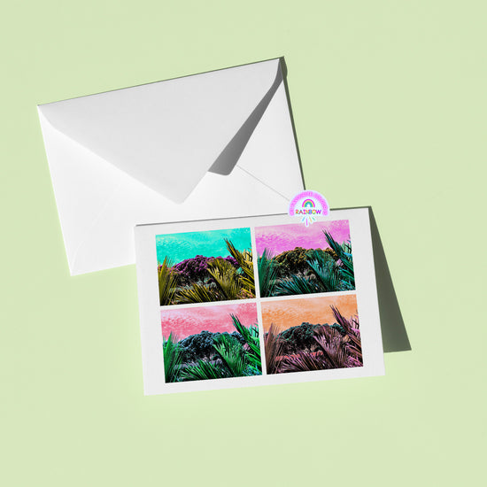 The Pohutukawa Pop Art greeting card (Version 3) from My Store showcases a vibrant landscape in four colorful sections. Its displayed on a light green background beside a white envelope and a Rainbow sticker.