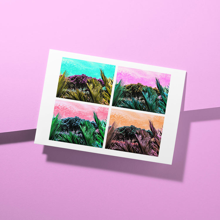 A vibrant greeting card, the Pohutukawa Pop Art (Version 3) from My Store, features four tropical-themed images with brilliant palm leaves and colorful skies on a textured pink surface, capturing New Zealands spirit.