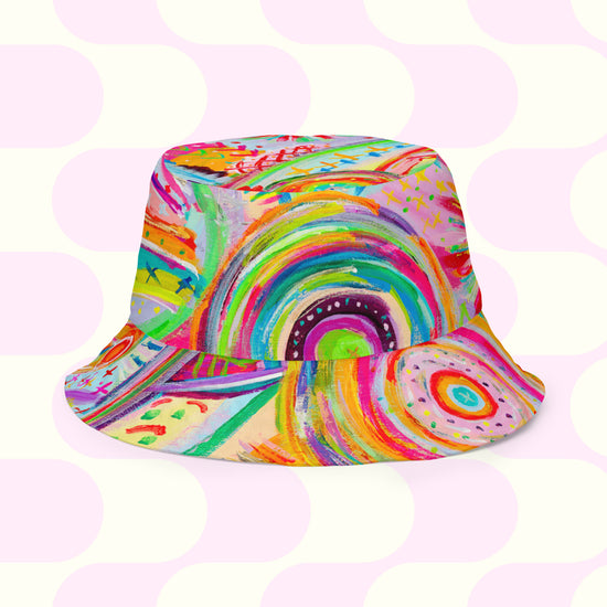 The Rainbow Connection/Summer Sorbet by My Favourite Colour is Rainbow is a vibrant reversible bucket hat featuring abstract swirls in pink, green, yellow, and orange. Style BFF offers a subtle pink and white geometric design in various sizes for a perfect fit.