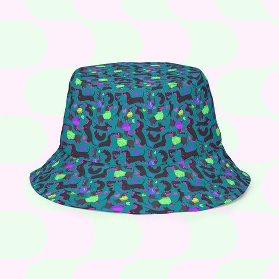 The Silly Sausages Green/Pink Reversible Bucket Hat by My Favourite Colour is Rainbow features a vibrant pattern of abstract shapes in green, pink, purple, and blue. Its playful design ensures style and comfort with large pastel circles, perfect for those adding fun to their wardrobe.