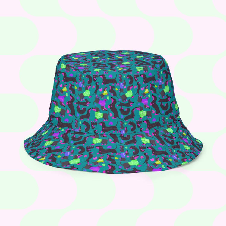 The Silly Sausages Green/Pink Reversible Bucket Hat by My Favourite Colour is Rainbow features a vibrant pattern of abstract shapes in green, pink, purple, and blue. Its playful design ensures style and comfort with large pastel circles, perfect for those adding fun to their wardrobe.