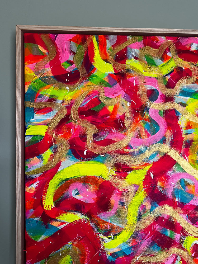 The Spaghetti Junction Framed Original Painting by My Store features vibrant swirling patterns in red, yellow, pink, green, and blue. Enhanced with neon and gold tones and a textured finish, this artwork is elegantly framed in wood against a gray wall.