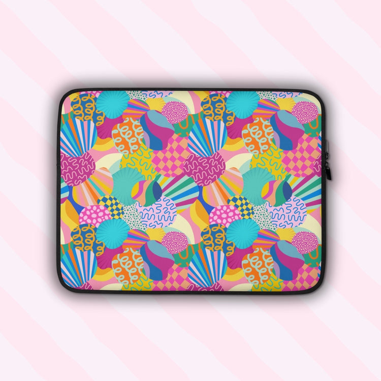 The Squiggs and Stripes Laptop Sleeve by My Favourite Colour is Rainbow features an abstract design of colourful geometric shapes, stripes and squiggles in pink, blue, orange yellow, and green.  It is shown on a pastel background.  The print is on only one side of the laptop sleeve, the other side is black.