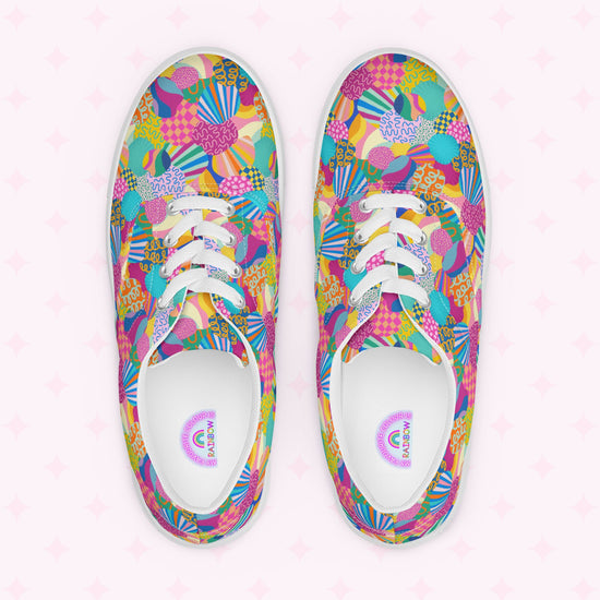 Top view of Squiggs and Stripes Canvas Sneakers by My Favourite Colour is Rainbow, showcasing a vibrant print in pink, blue, yellow, and green shapes. White laces match the inner soles text and graphics. The faint pink star-decorated background enhances the vibrant style.