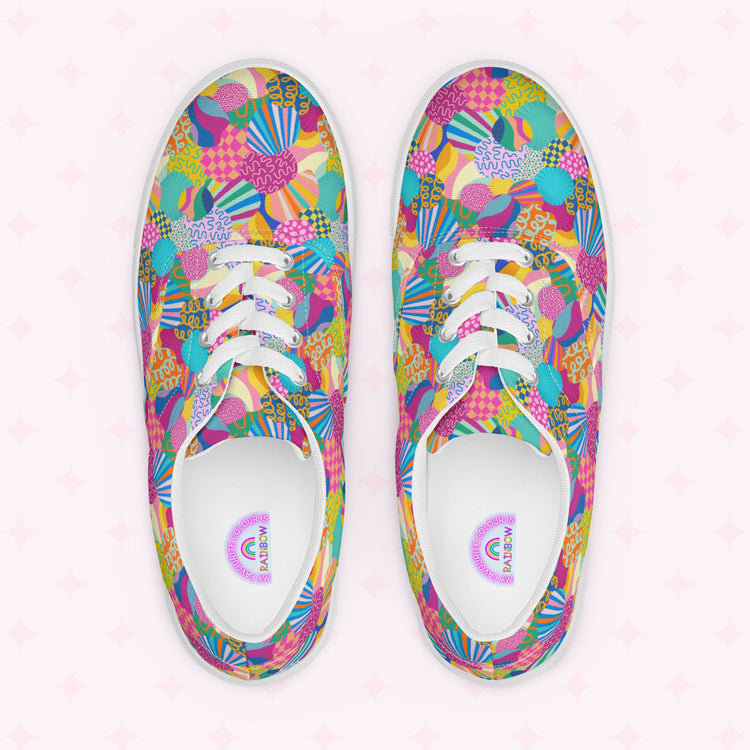 Top view of Squiggs and Stripes Canvas Sneakers by My Favourite Colour is Rainbow, showcasing a vibrant print in pink, blue, yellow, and green shapes. White laces match the inner soles text and graphics. The faint pink star-decorated background enhances the vibrant style.