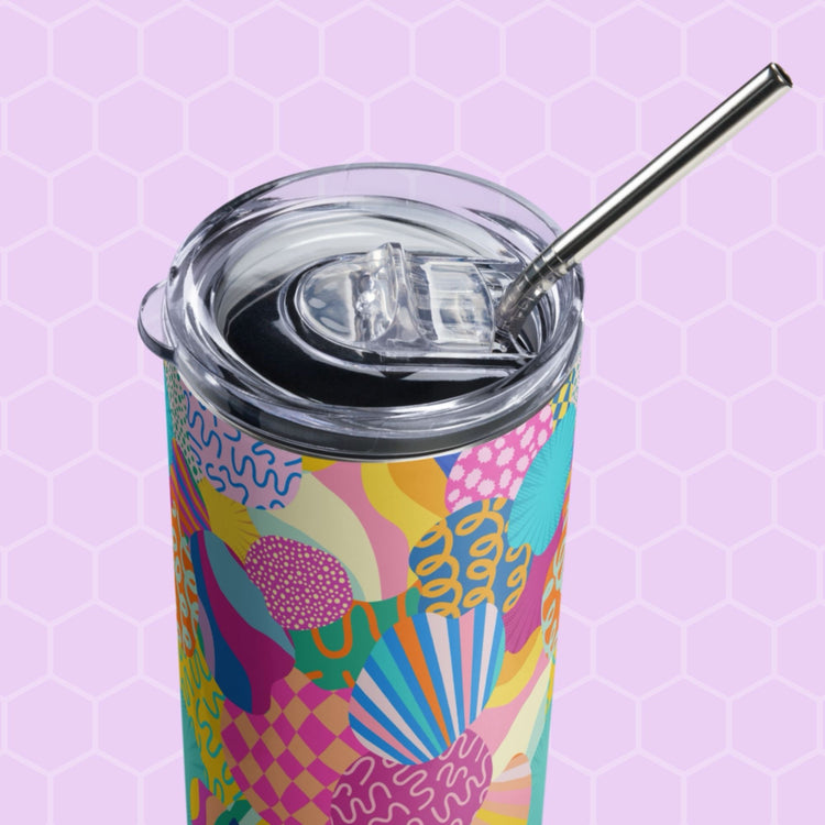 The Squiggs and Stripes Stainless Steel Tumbler by My Favourite Colour is Rainbow features colorful abstract patterns, a metal straw, and a transparent lid on a light purple hexagonal background.