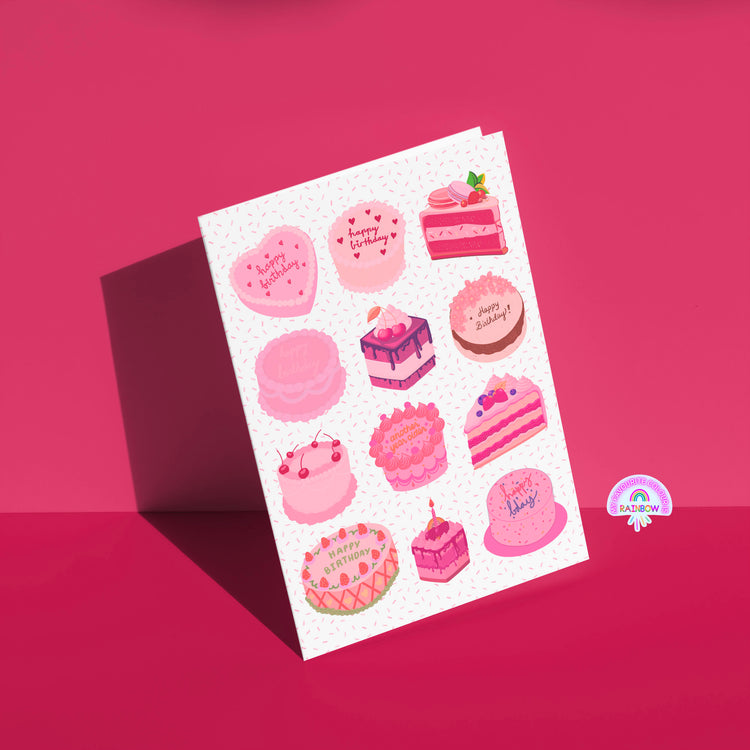 The Sweet Treats Birthday Card by My Store features a red background with charming pink and purple cake designs, some with Happy Birthday messages. A whimsical rainbow logo adorns the bottom right corner.