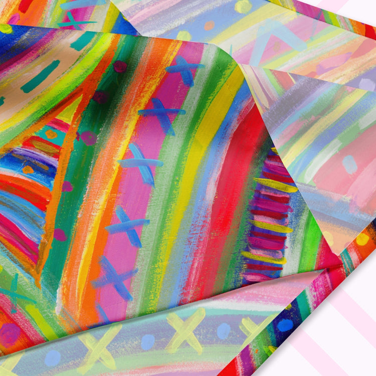 A closeup of the Rainbow Connection Bandana by My Favourite Colour is Rainbow featuring a vibrant, abstract pattern with bold rainbow hues.  The design is printed on only one side of the bandana.
